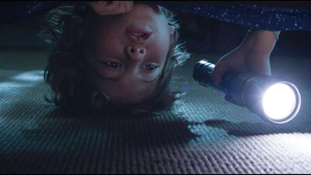 a child lying on the floor with a flashlight